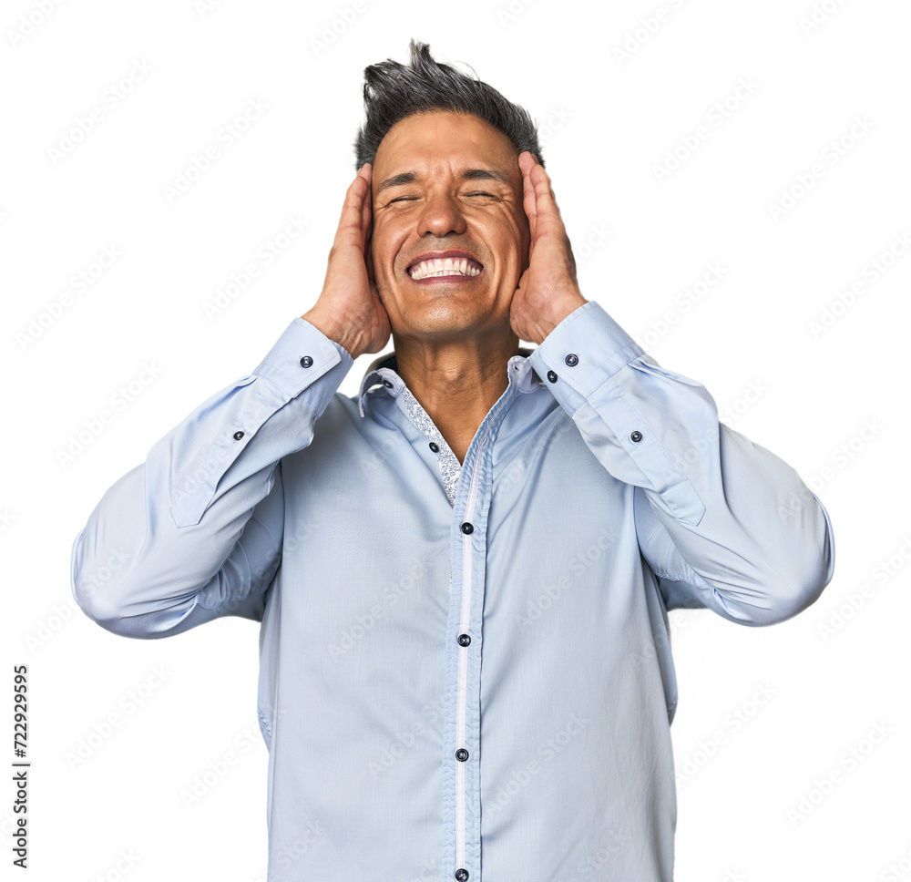 Middle-aged Latino man laughs joyfully keeping hands on head. Happiness concept. Middle-aged Latino man laughs joyfully keeping hands on head. Happiness concept.