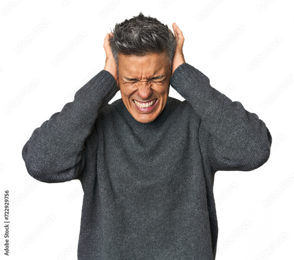 Middle-aged Latino man covering ears with hands trying not to hear too loud sound. Middle-aged Latino man covering ears with hands trying not to hear too loud sound.
