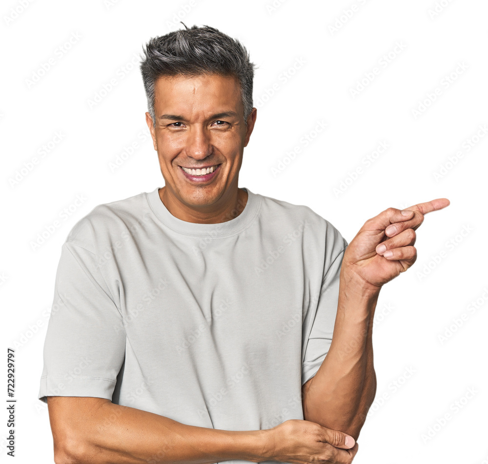 Middle-aged Latino man smiling cheerfully pointing with forefinger away. Middle-aged Latino man smiling cheerfully pointing with forefinger away.