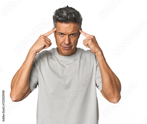 Middle-aged Latino man focused on a task, keeping forefingers pointing head.