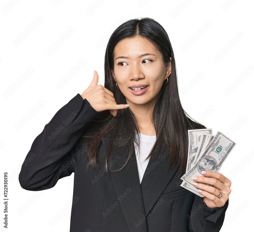 Young Chinese woman with dollars in suit showing a mobile phone call gesture with fingers. Young Chinese woman with dollars in suit showing a mobile phone call gesture with fingers.