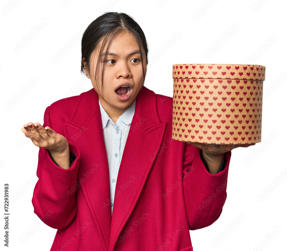 Young Chinese woman holding a heart-filled box surprised and shocked. Young Chinese woman holding a heart-filled box surprised and shocked.