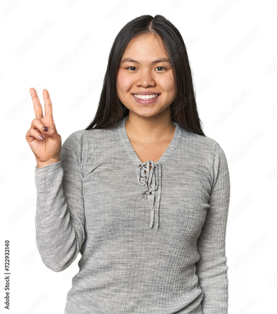 Young chinese woman isolated showing victory sign and smiling broadly.