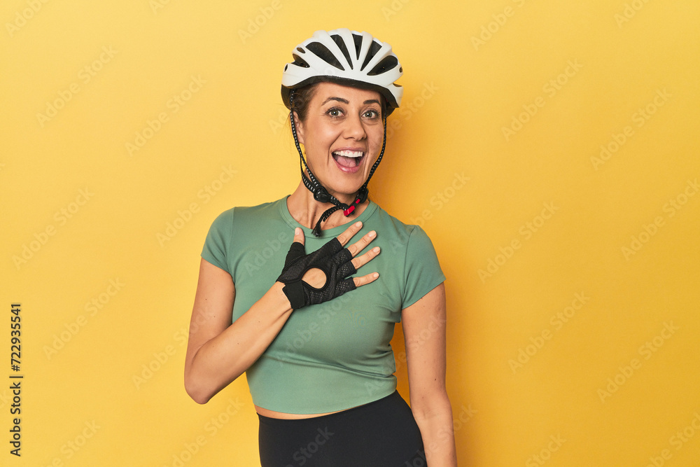 Cyclist middle aged woman with helmet and gloves posed laughs out loudly keeping hand on chest. Cyclist middle aged woman with helmet and gloves posed laughs out loudly keeping hand on chest.