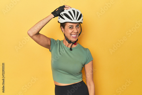 Cyclist middle aged woman with helmet and gloves posed being shocked, she has remembered important meeting.