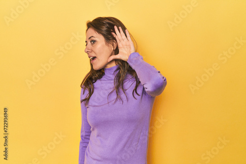 Middle-aged caucasian woman on yellow trying to listening a gossip.