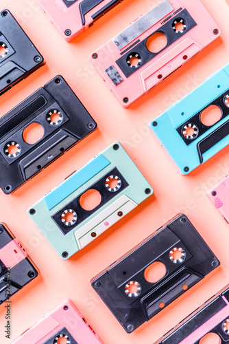 Flat lay shot of 80's music cassettes lined up on a pastel pink background. Nostalgia concept.