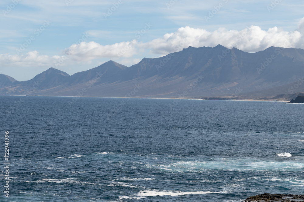 View on difficult to access golden sandy long Cofete beach hidden behind mountain range on Fuerteventura, Canary islands, Spain View on difficult to access golden sandy long Cofete beach hidden behind mountain range on Fuerteventura, Canary islands, Spain