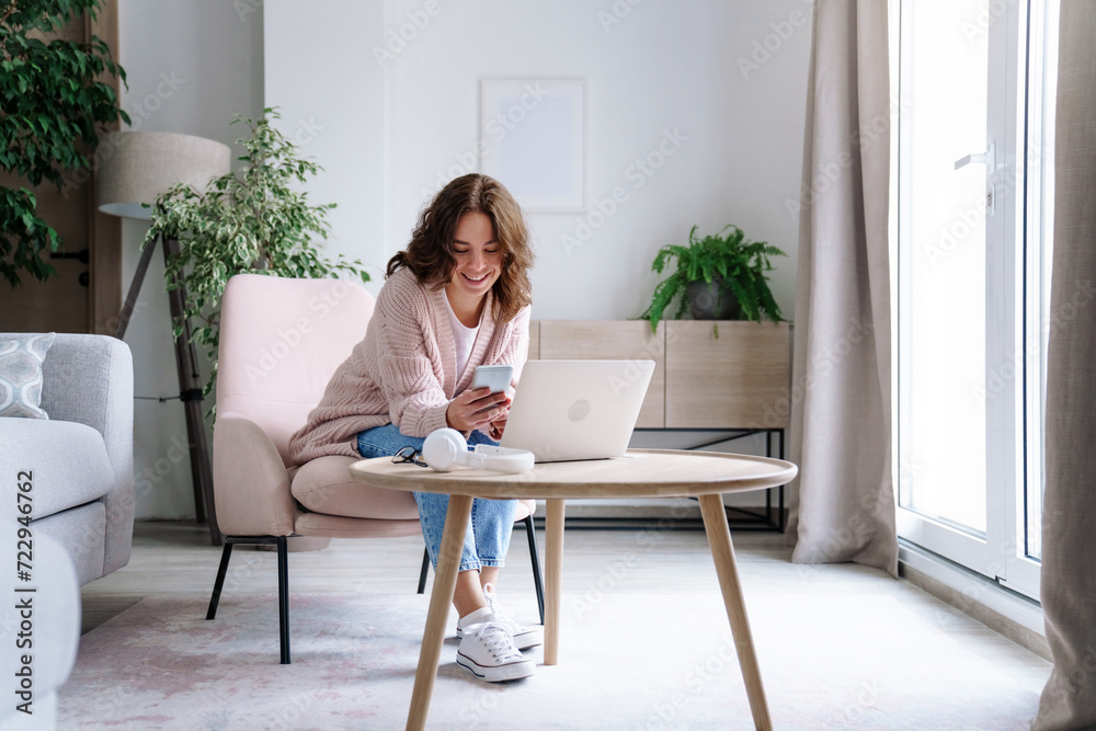 Young woman working from home office. Freelancer using laptop, phone and Internet. Workplace in cozy living room. Education, distance learning. Student shopping online. Technology lifestyle. Young woman working from home office. Freelancer using laptop, phone and Internet. Workplace in cozy living room. Education, distance learning. Student shopping online. Technology lifestyle.