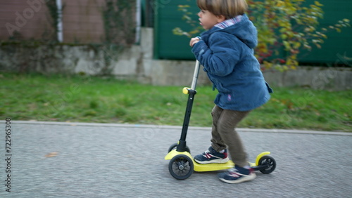 Active Three-Year-Old Boy Enjoying Ride on Three-Wheeled Scooter Outdoors