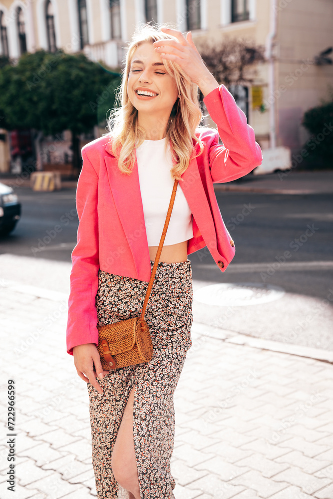 Young beautiful smiling blond hipster woman in trendy summer clothes. Sexy carefree female posing in the street at sunny day. Positive model outdoors at sunset. Cheerful and happy