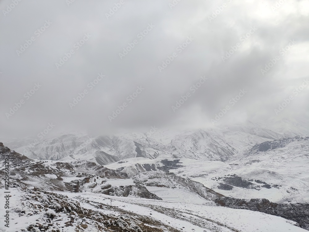 snow covered mountains with foggy sky, snowing