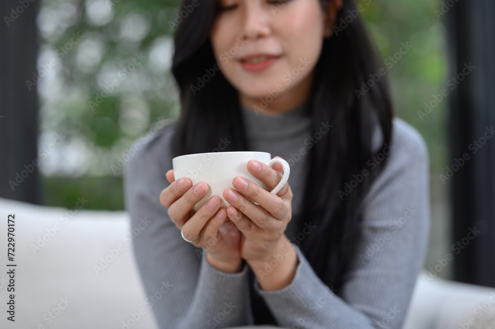 Selective focus of relaxed happy young woman's hands holding coffee cup on sofa at home Smiling girl on holiday Selective focus of relaxed happy young woman's hands holding coffee cup on sofa at home Smiling girl on holiday