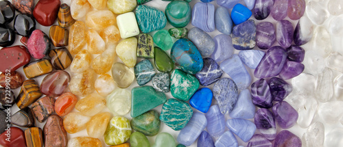 Chakra Crystal Healing wide Background template - Rows of tumbled polished healing crystal laid out in chakra colours white, purple, blue, green, yellow, orange, red ideal for crystal healing theme
