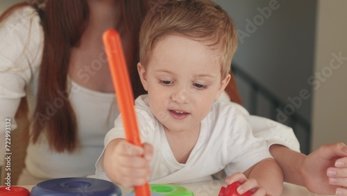 the child collects a toy pyramid. mom plays with son at home happy family. development of fine motor skills in a newborn child. fun happy family mom and baby play pyramid game. preschool education