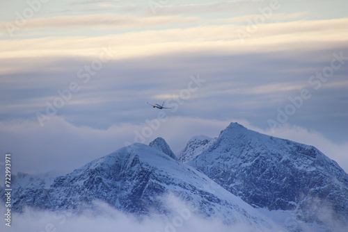 airplane in the air next to a moutain