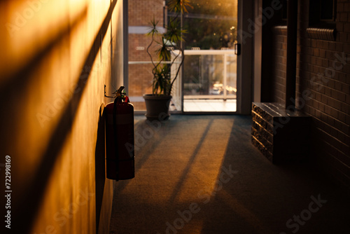 Silhouette of fire extinguisher in motel hallway illuminated by golden afternoon sunlight photo