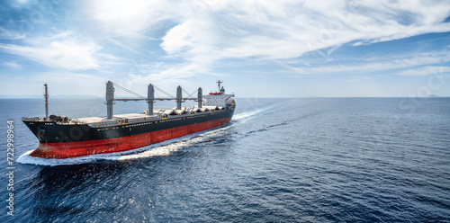 Fototapeta Naklejka Na Ścianę i Meble -  Aerial view of a bulk carrier cargo vessel traveling with high speed over blue sea with copy space as a concept for import and export industry