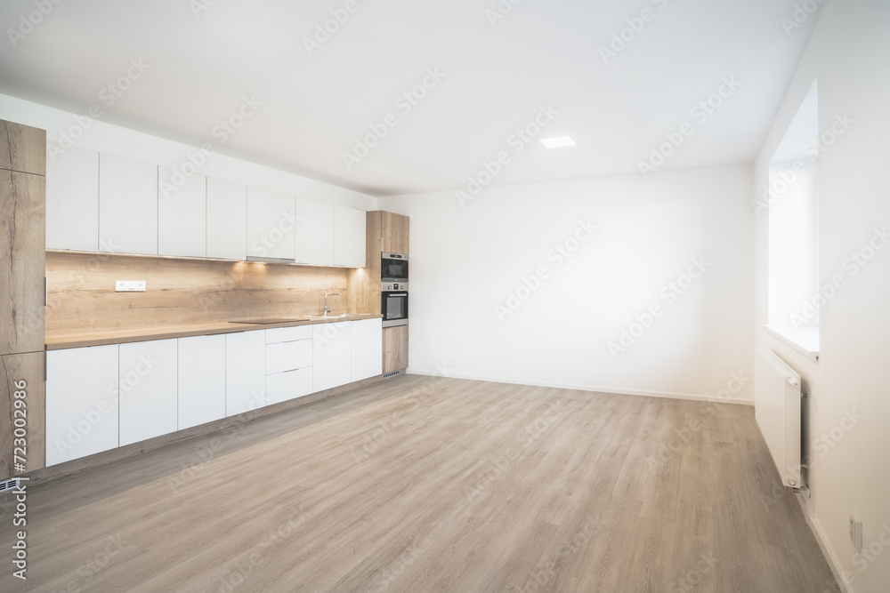Fototapeta premium A Modern kitchen with white cabinets, a wooden countertop, built-in appliances, and a spacious layout.