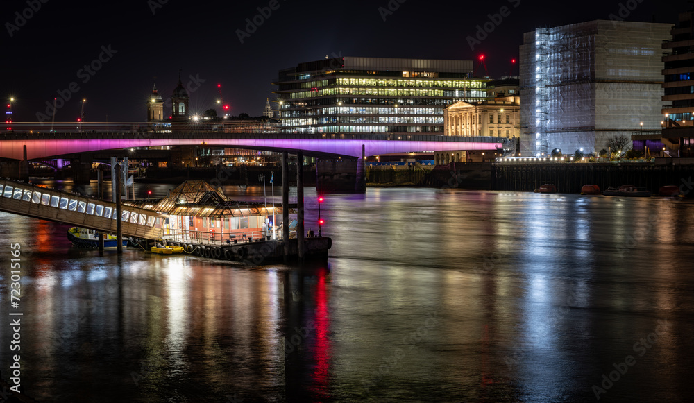  A night time view of London Bridge with colourful reflections on the water of the Thames River.