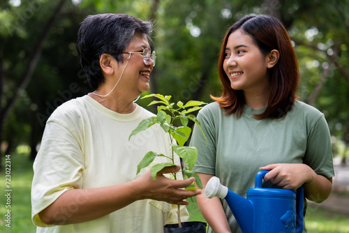 Portrait, Asian family mom and daughter plant sapling tree outdoors in nature park, Concept of happy retirement With care from a caregiver and Savings and senior health insurance, Happy family