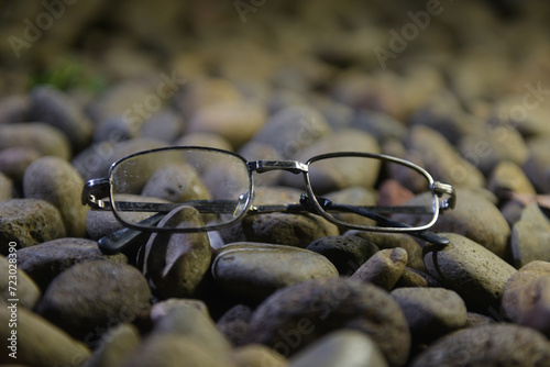 old glasses with black optical frames made of iron are among the rocks