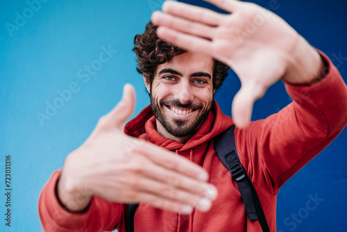 Happy man making finger frame in front of blue wall photo