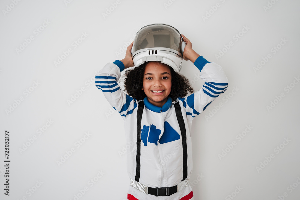 Smiling girl wearing space helmet in front of white wall Smiling girl wearing space helmet in front of white wall