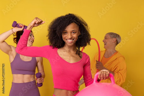 Smiling woman flexing muscles standing with friends against yellow background photo