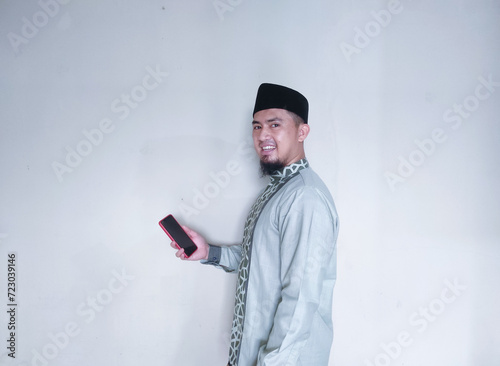 Photography Muslim Asian man smiling looking at camera while holding smartphone