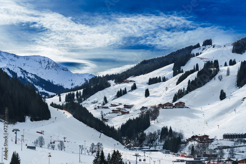 A picturesque snowy landscape showcasing a ski resort nestled in the alpine mountains, under a partly cloudy sky, perfect concept for winter holidays, skiing adventures and mountain retreats