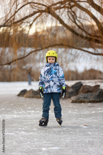 Happy child, boy, skating during the day on frozen lake, having fun © Tomsickova