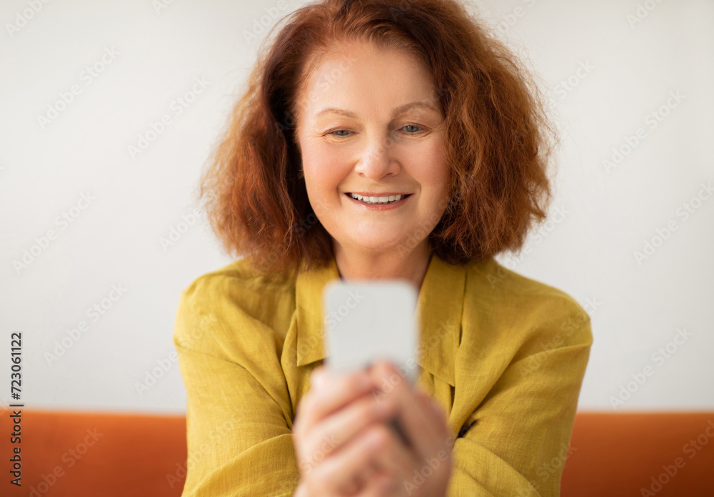 Closeup shot of smiling senior woman using her smartphone at home Closeup shot of smiling senior woman using her smartphone at home