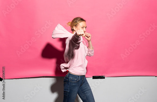 Woman in hooded shirt punching in studio