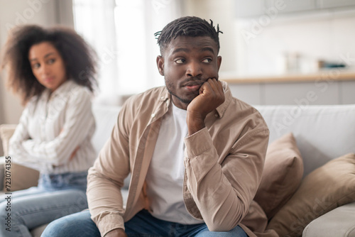 African spouses ignoring each other after quarrel sitting apart indoor