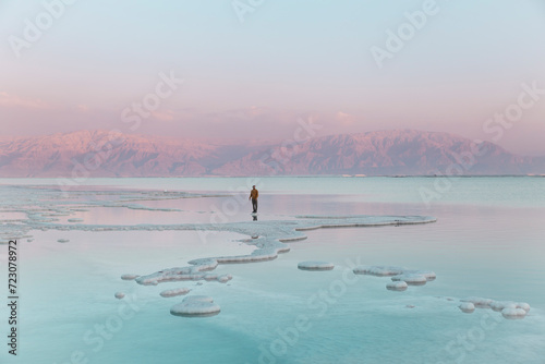 Man standing on salt formations in dead sea photo