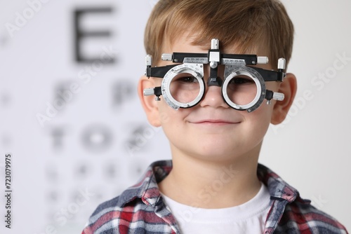 Little boy with trial frame against vision test chart photo