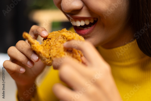 Happy young asian woman eating delicious fried chicken at home.