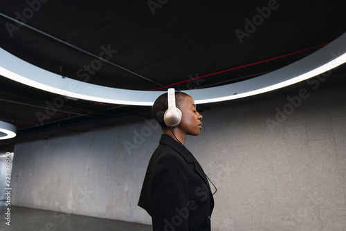 Young woman listening music on headphones in parking garage photo