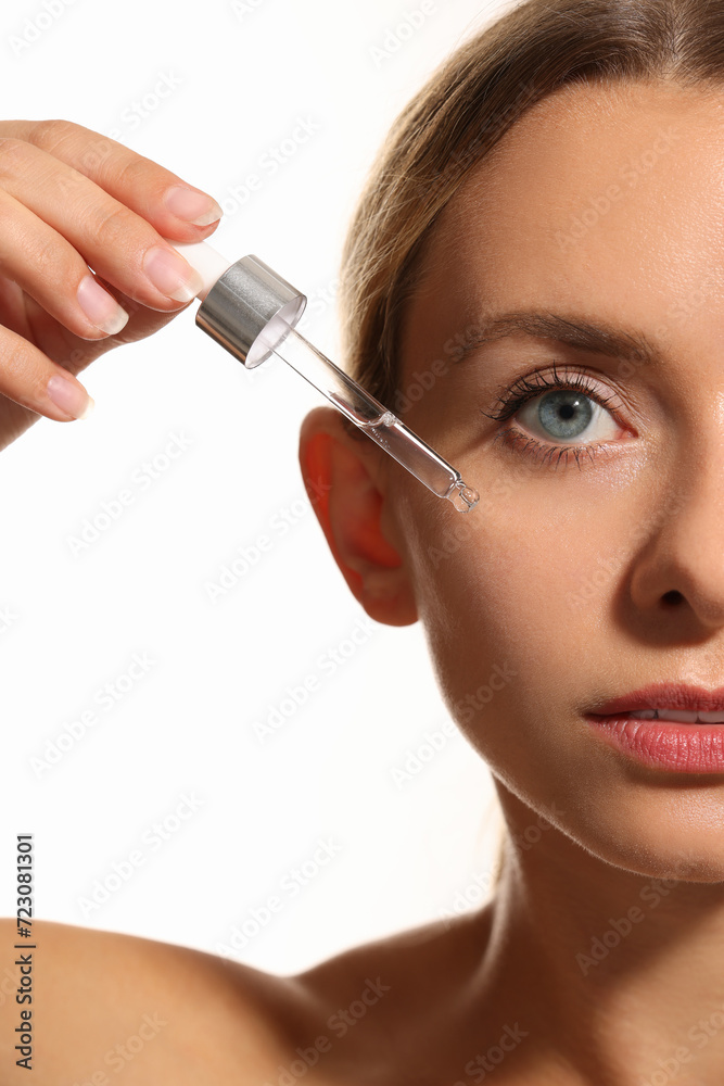 Woman applying cosmetic serum onto her face on white background, closeup Woman applying cosmetic serum onto her face on white background, closeup