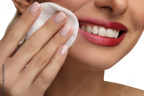 Smiling woman removing makeup with cotton pad on white background  closeup