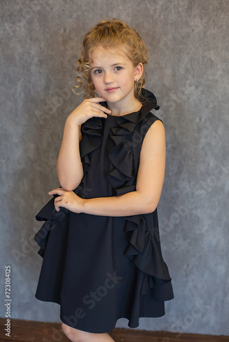 blonde girl with a ponytail on her head in a beautiful black dress on a black background