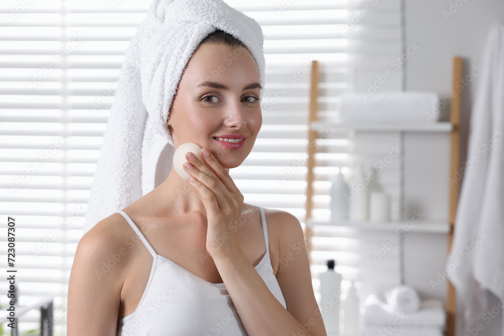 Happy young woman washing her face with sponge in bathroom. Space for text Happy young woman washing her face with sponge in bathroom. Space for text