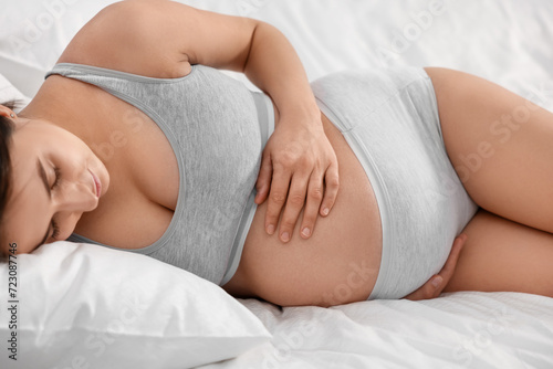 Beautiful pregnant woman in comfortable maternity underwear lying on bed