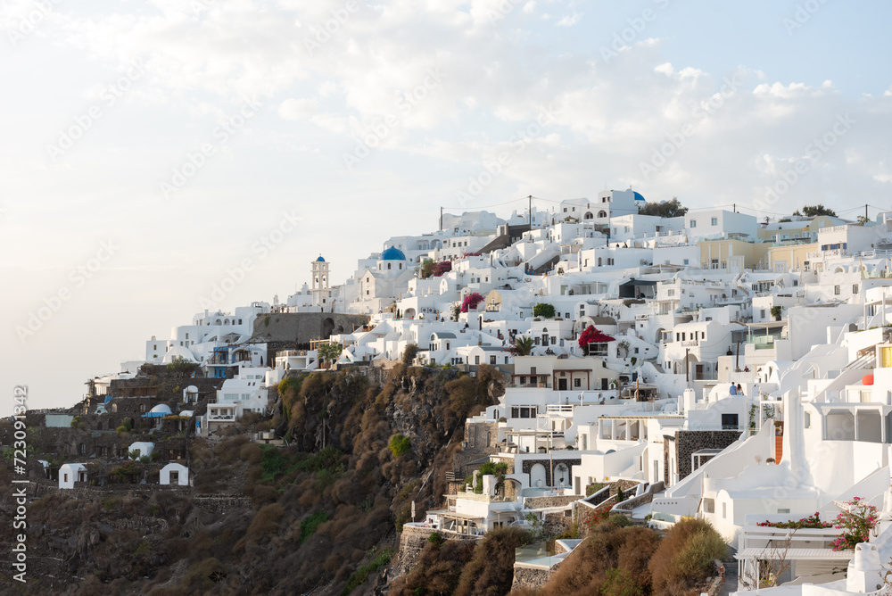 View of Imerovigli village in Santorini with white washed buildings with blue dome church and blue sky