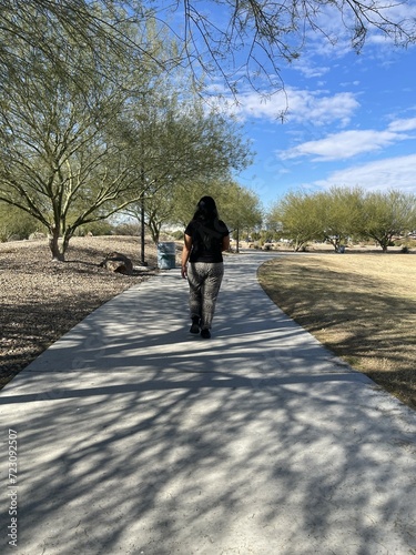Lady Walking on Sidewalk Trail at a Park