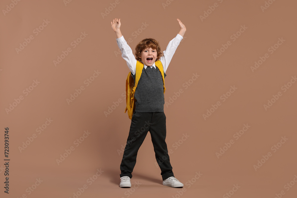 Emotional schoolboy with backpack on brown background Emotional schoolboy with backpack on brown background