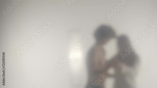 Blurred silhouette of a couple dancing a waltz behind a transparent frosted glass or curtain. Concept of ghosts and spirits, the afterlife and the otherworld. HDR BT2020 HLG Material. photo