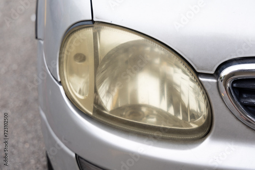 Hazy opaque yellowed front head lamp of car reduces light pass-through and driving visibility