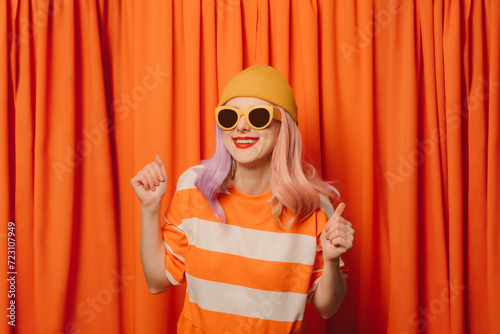 Happy woman with clenched fists dancing in front of orange curtain